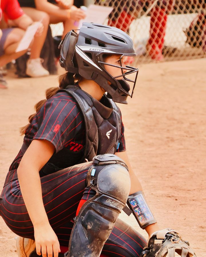 Mia Mead set in the crouch behind the plate in full catching gear